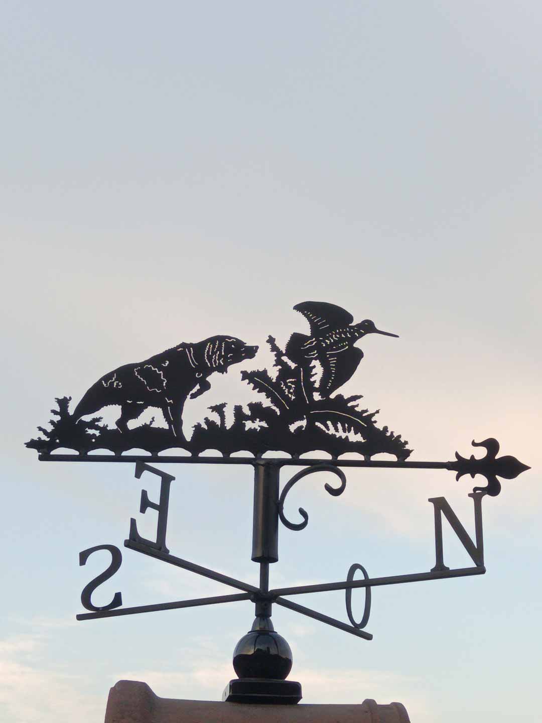 Une girouette représentant une scène de chasse avec un chien pistant un oiseau